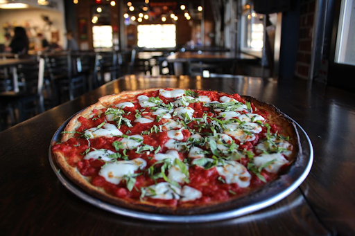 A Neapolitan style pizza with fresh mozzarella and basil on a table at Little Miami Brewing Company, featuring a vibrant red sauce and crispy crust.