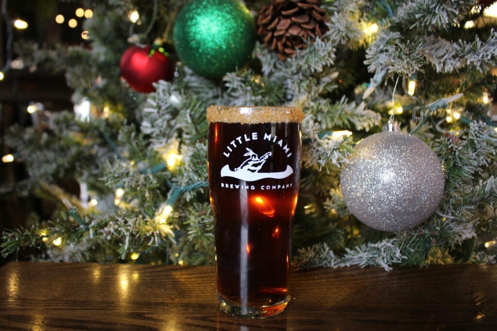 A glass of Little Miami Brewing Company's flavored beer A glass of Little Miami Brewing Company's flavored beer with a festive holiday rim, set against a decorated Christmas tree.